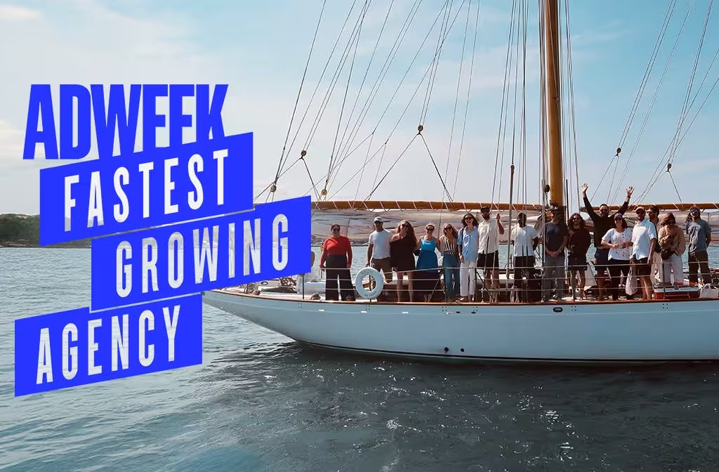 Team celebrating on a sailboat with Adweek Fastest Growing Agency award text overlay