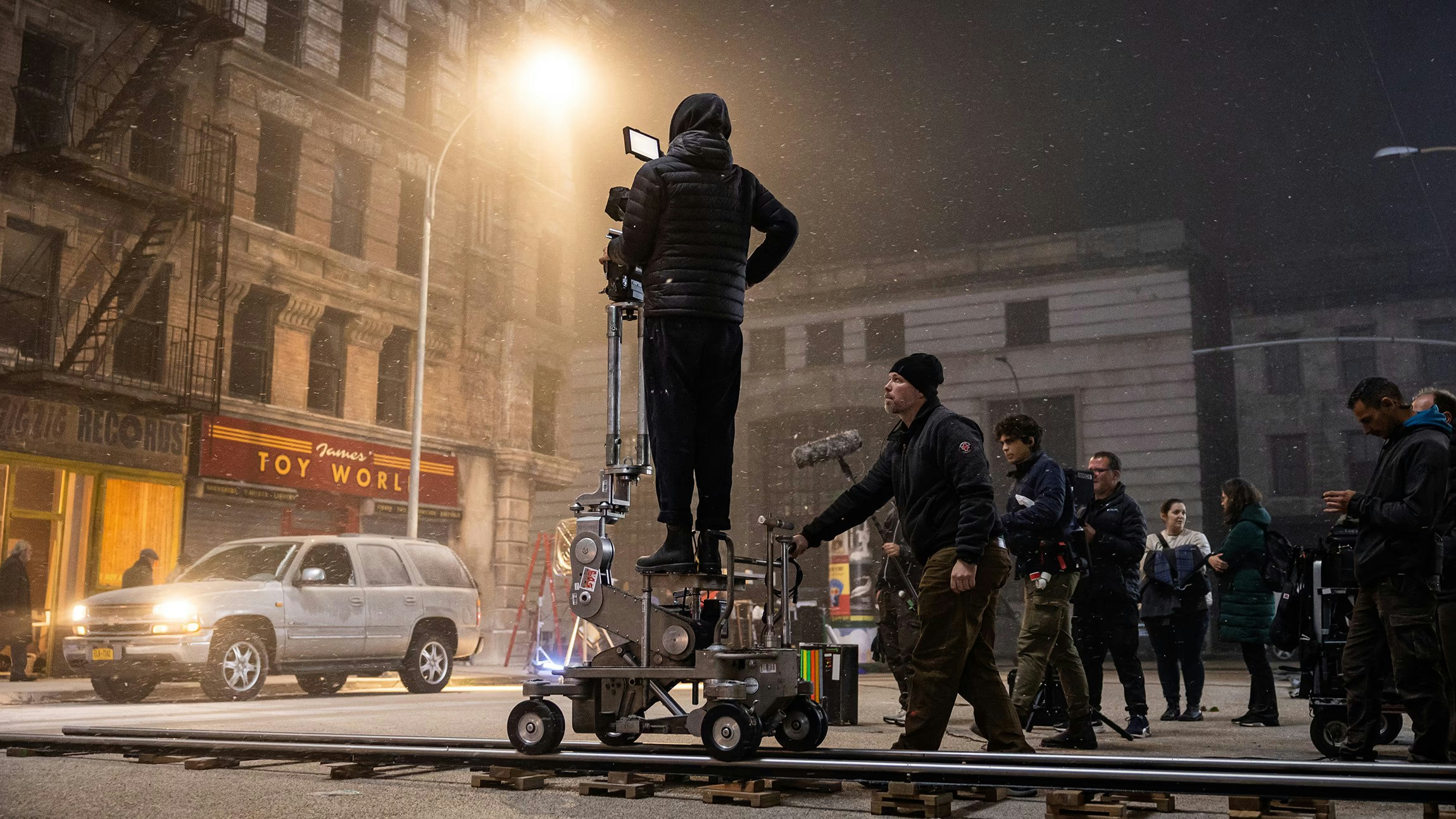 Film crew working on a snowy nighttime street set with camera equipment