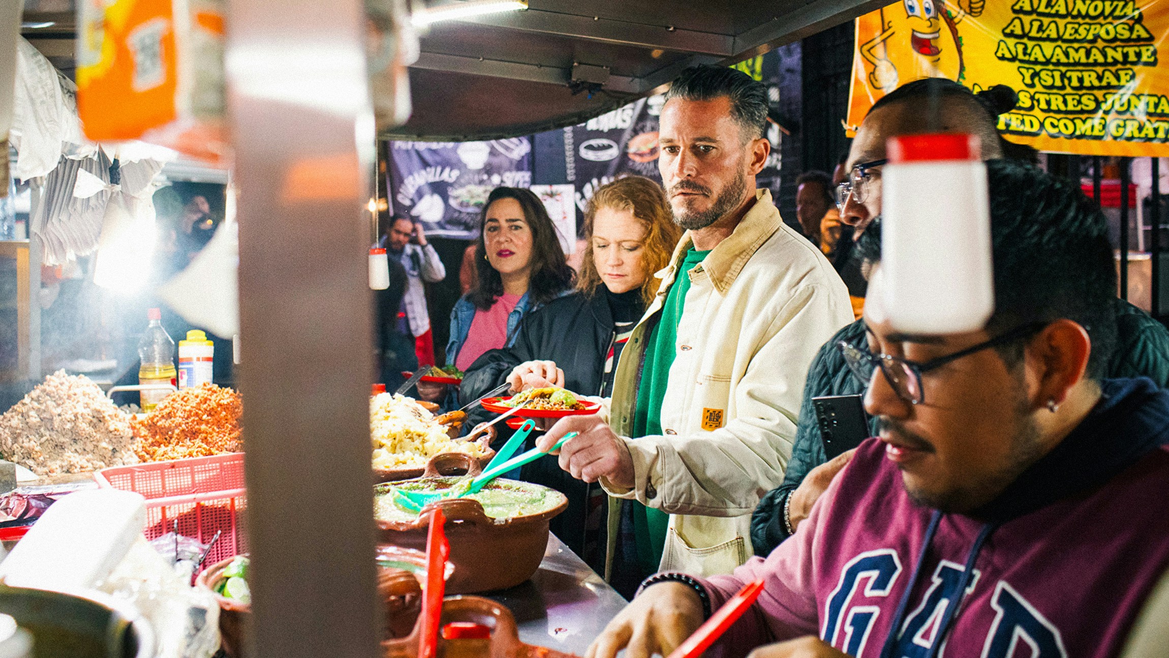 Group enjoying late-night street tacos at a bustling Mexico City food stand